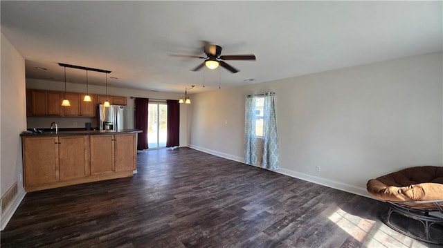 kitchen featuring dark wood-style floors, brown cabinets, stainless steel refrigerator with ice dispenser, dark countertops, and open floor plan