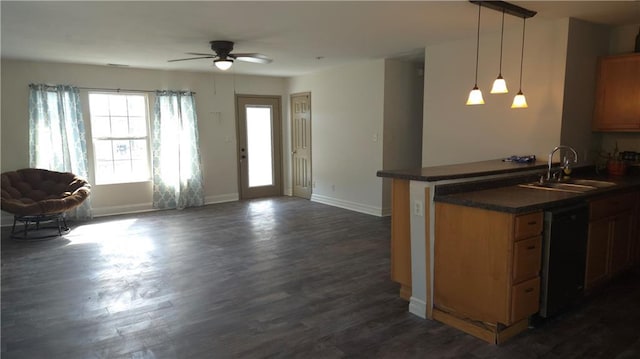 kitchen with dark countertops, dark wood-type flooring, open floor plan, dishwashing machine, and a sink