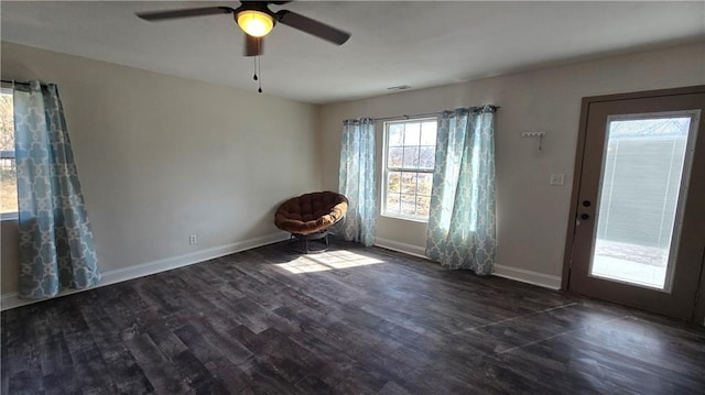 interior space with dark wood finished floors, visible vents, a ceiling fan, and baseboards