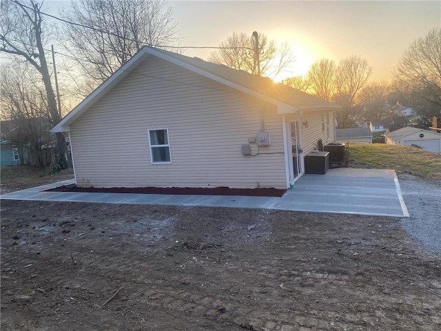 property exterior at dusk featuring cooling unit and a patio