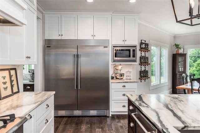 kitchen featuring light stone counters, dark hardwood / wood-style flooring, built in appliances, crown molding, and white cabinets