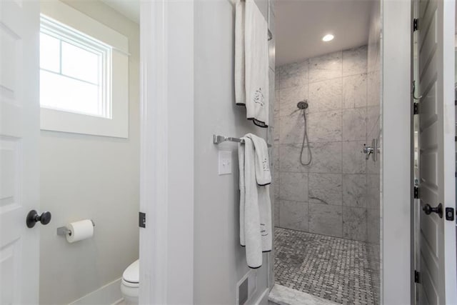 bathroom featuring a tile shower and toilet