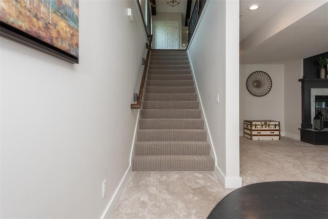 stairs with carpet flooring and a fireplace