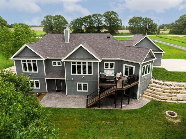 rear view of property with a wooden deck, a yard, a patio, and an outdoor fire pit