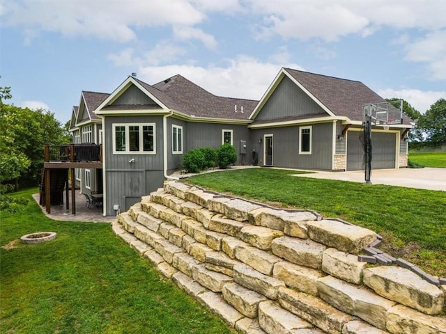 back of house featuring a lawn, a wooden deck, and an outdoor fire pit