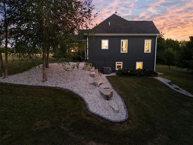 back house at dusk featuring a lawn