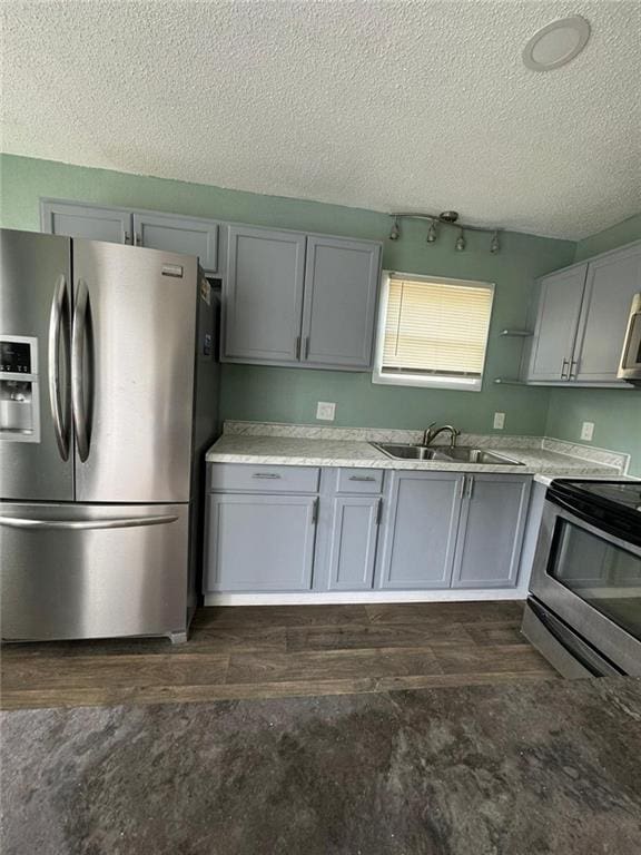 kitchen featuring appliances with stainless steel finishes, a textured ceiling, sink, and gray cabinetry