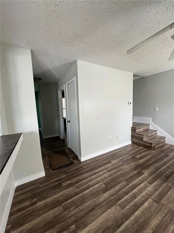 unfurnished living room with ceiling fan, a textured ceiling, and dark hardwood / wood-style flooring