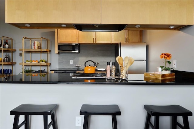 kitchen with stainless steel appliances, kitchen peninsula, decorative backsplash, and a breakfast bar