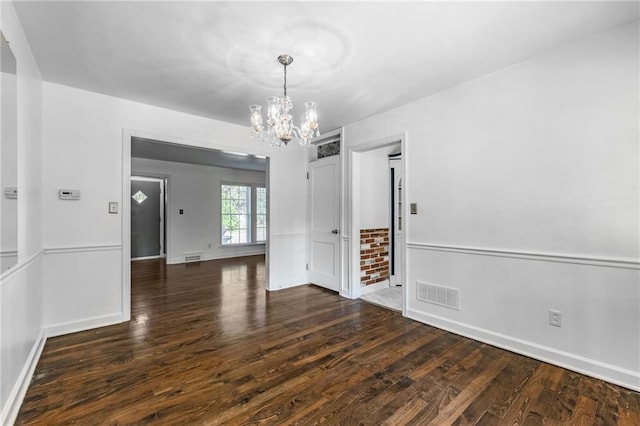 empty room featuring a chandelier and dark hardwood / wood-style flooring