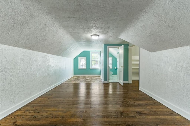 bonus room with a textured ceiling, vaulted ceiling, and dark hardwood / wood-style floors