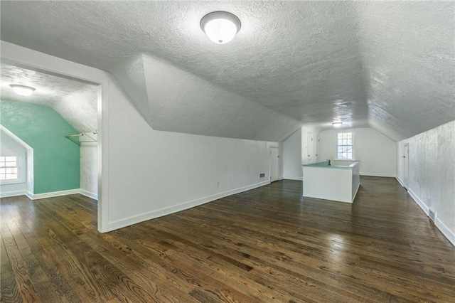 additional living space with a textured ceiling, dark hardwood / wood-style floors, and plenty of natural light