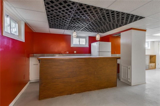 bar featuring white refrigerator and a drop ceiling