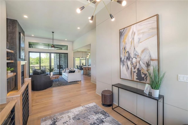 interior space with a large fireplace, ceiling fan, and light wood-type flooring