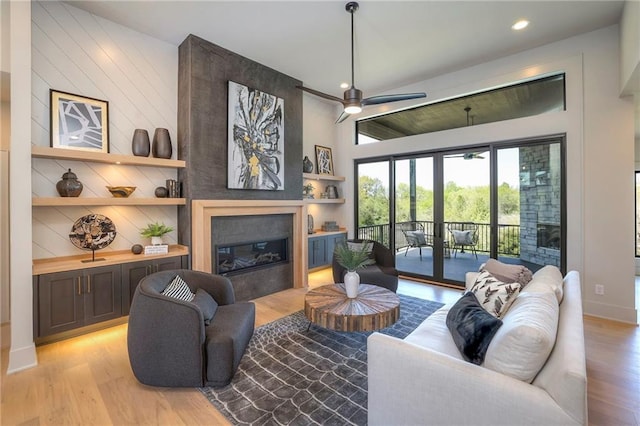 living room featuring ceiling fan, a fireplace, vaulted ceiling, and light hardwood / wood-style flooring