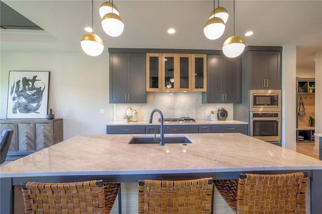 kitchen featuring light stone counters, hanging light fixtures, sink, tasteful backsplash, and stainless steel appliances