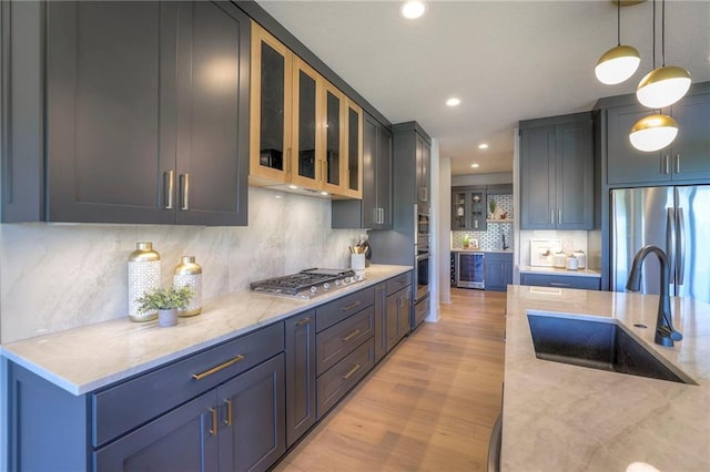 kitchen featuring light hardwood / wood-style floors, sink, hanging light fixtures, stainless steel appliances, and backsplash