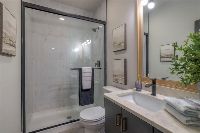 bathroom featuring vanity, a shower with shower door, and toilet