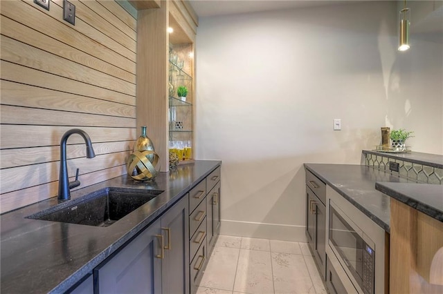 kitchen featuring light tile patterned floors, dark stone counters, stainless steel microwave, and sink