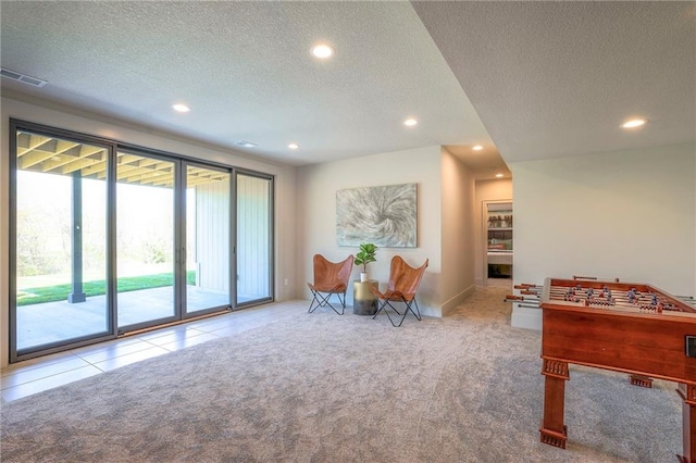 rec room featuring light carpet and a textured ceiling