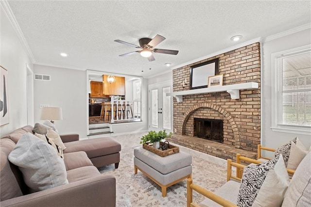 living room featuring a brick fireplace, a textured ceiling, and ornamental molding