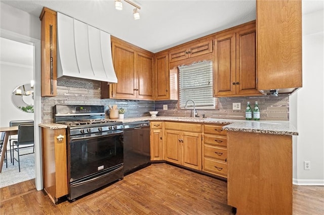 kitchen featuring black appliances, light hardwood / wood-style floors, sink, and tasteful backsplash