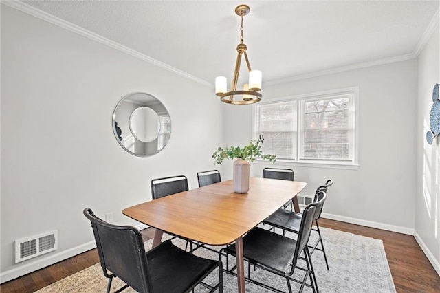 dining space featuring crown molding, dark wood-type flooring, and a chandelier