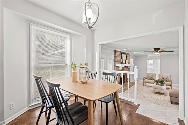 dining space featuring a brick fireplace, ceiling fan with notable chandelier, and hardwood / wood-style flooring