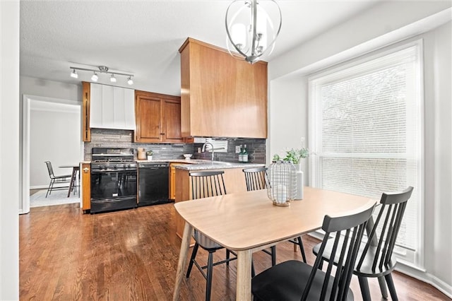 kitchen featuring dark hardwood / wood-style floors, sink, black appliances, and decorative light fixtures