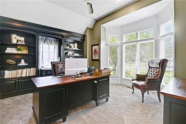 carpeted office space featuring ceiling fan, built in features, and vaulted ceiling