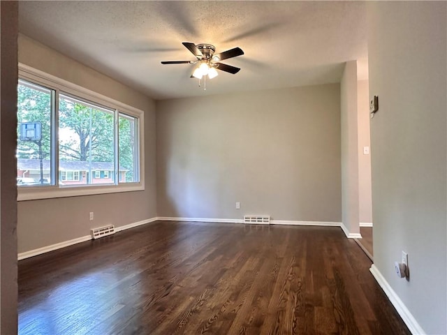 empty room with dark wood-type flooring, a textured ceiling, and ceiling fan