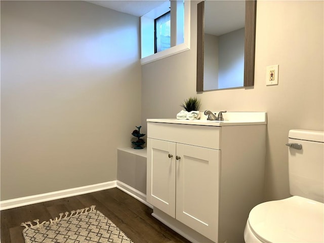 bathroom with toilet, vanity, and wood-type flooring