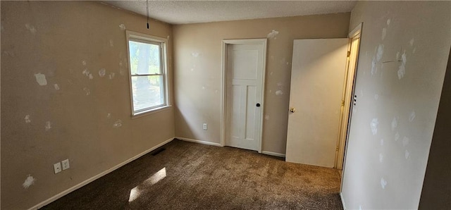 unfurnished bedroom with dark carpet and a textured ceiling