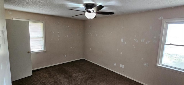 empty room featuring ceiling fan, a textured ceiling, and dark carpet