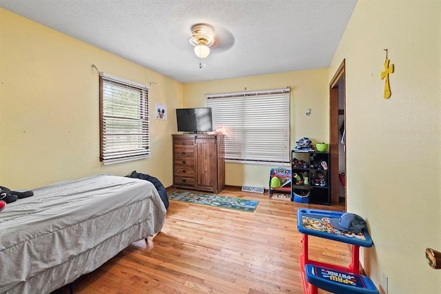 bedroom featuring ceiling fan, a textured ceiling, and light hardwood / wood-style floors