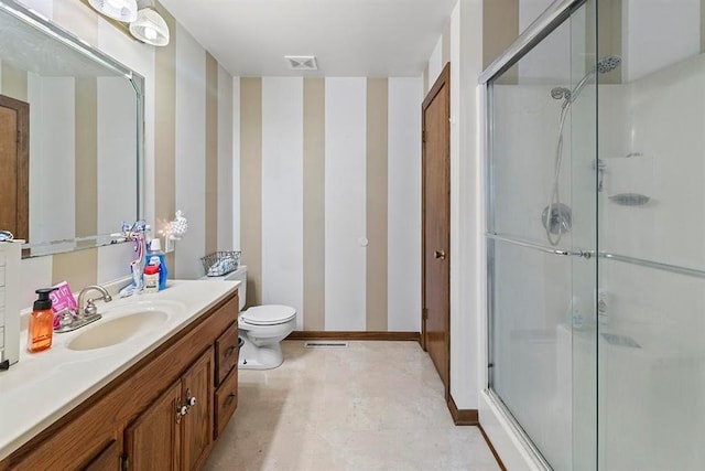 bathroom featuring a shower with shower door, vanity, and toilet