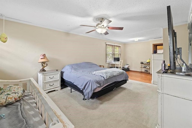 carpeted bedroom featuring ceiling fan, a textured ceiling, and crown molding