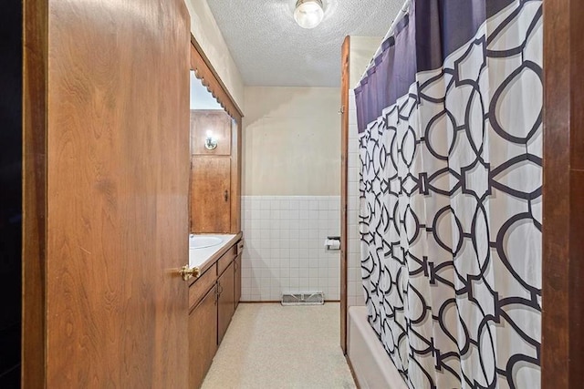 bathroom featuring tile walls, shower / bath combo, a textured ceiling, and vanity