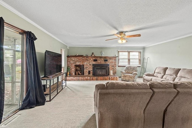 carpeted living room featuring a brick fireplace, ceiling fan, crown molding, and a textured ceiling