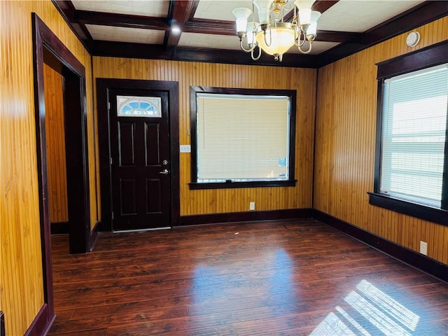 entryway with coffered ceiling, an inviting chandelier, wood walls, and dark hardwood / wood-style floors