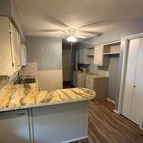 kitchen with ceiling fan, white cabinets, kitchen peninsula, stainless steel dishwasher, and dark hardwood / wood-style flooring