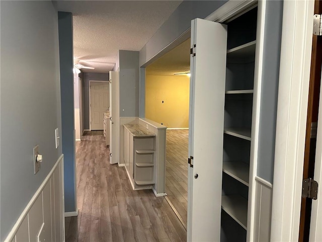 corridor featuring a textured ceiling and hardwood / wood-style floors