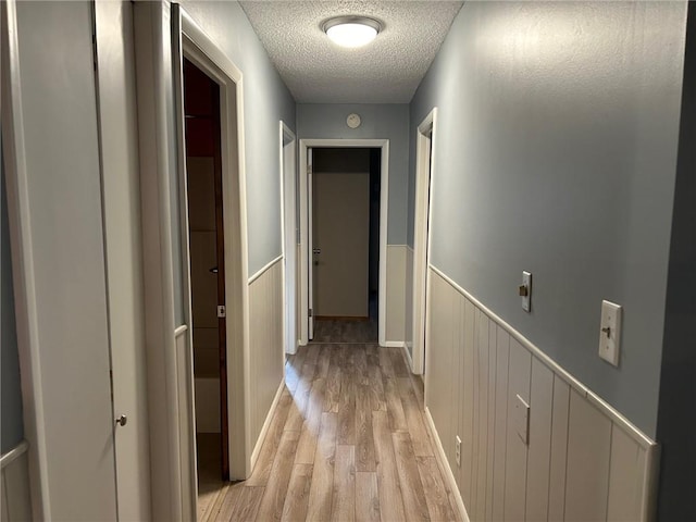 hall with light hardwood / wood-style flooring and a textured ceiling