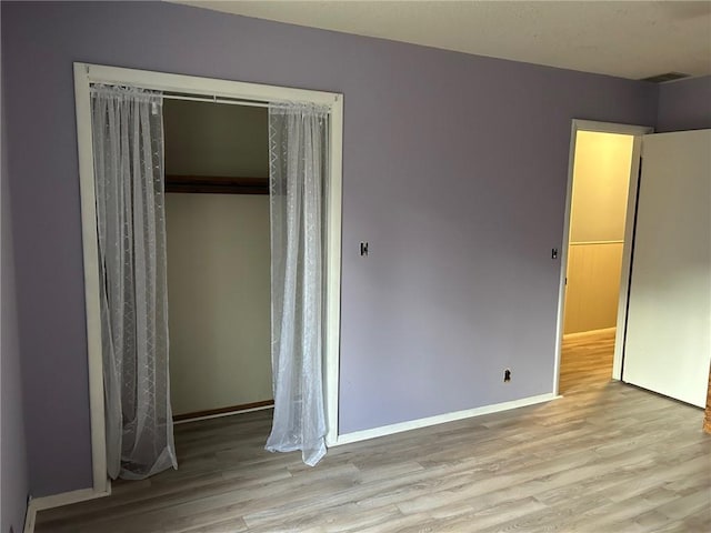 unfurnished bedroom with light wood-type flooring and a closet