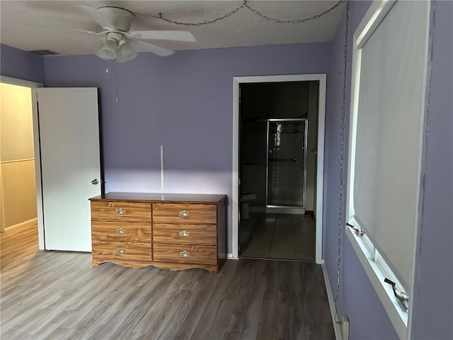 unfurnished bedroom with a closet, a textured ceiling, wood-type flooring, ceiling fan, and ensuite bath