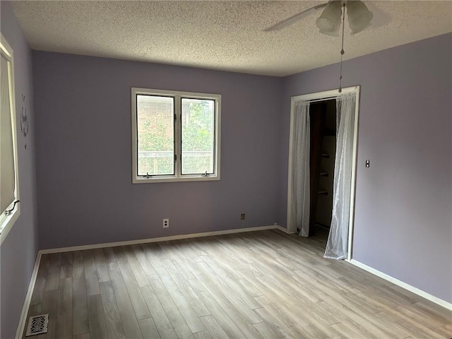 spare room featuring light hardwood / wood-style flooring, ceiling fan, and a textured ceiling