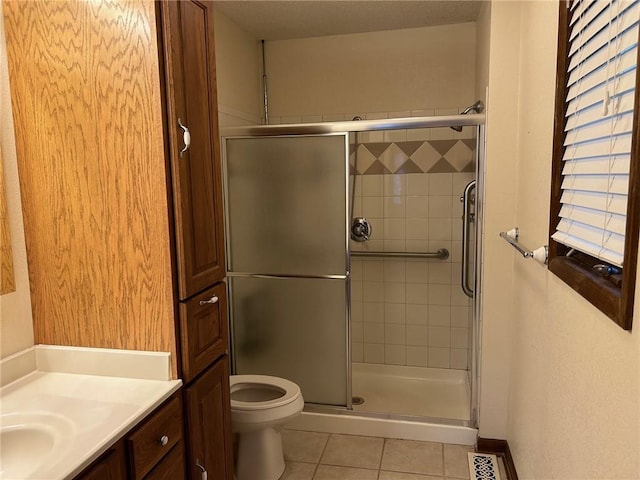 bathroom featuring tile patterned floors, walk in shower, vanity, and toilet