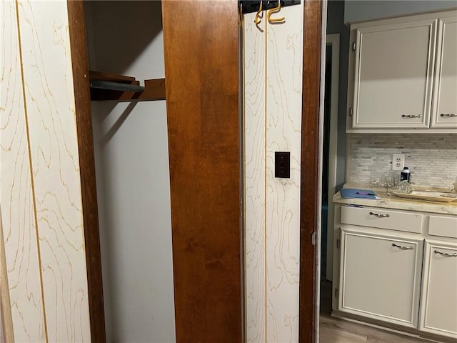 interior space with decorative backsplash, wood-type flooring, and white cabinets