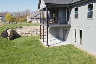 rear view of property with a balcony, a yard, and a patio area