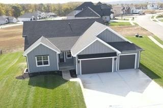 single story home featuring concrete driveway, an attached garage, and a front lawn